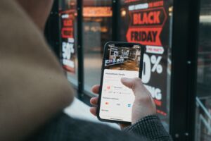 A phone screen shows black friday deals against a retail backdrop