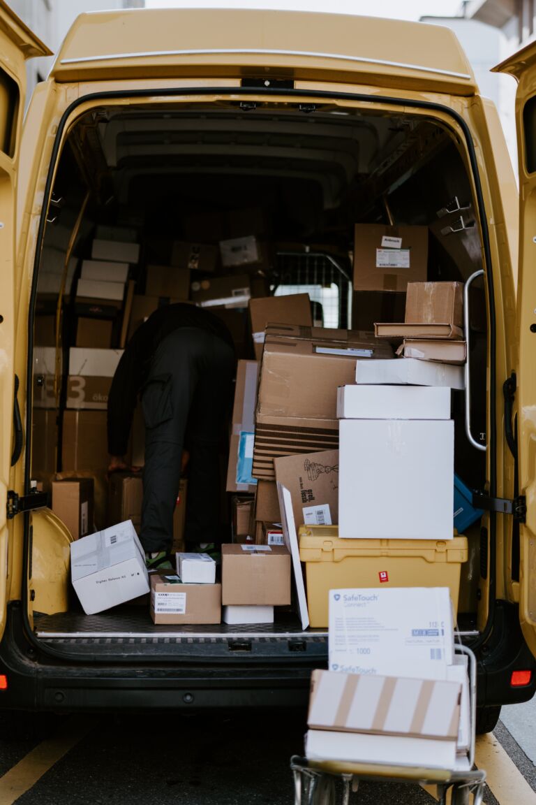 A view into the back of a couriers van, filled with cardboard boxes of different sizes
